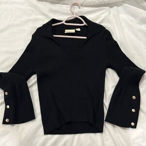 Full length black top with collar and flared sleeves containing gold buttons.